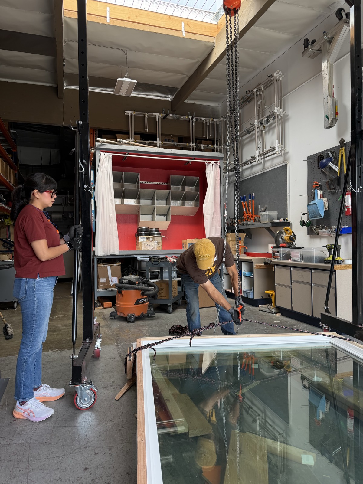 Technicians rigging a large glass unit with chain hoists in the test lab